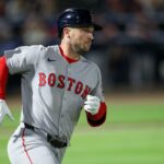 Um jogador do Boston Red Sox usando capacete e uniforme cinza com