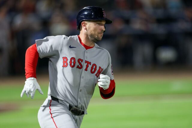 Um jogador do Boston Red Sox usando capacete e uniforme cinza com 
