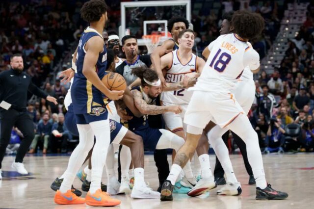 Vários jogadores de basquete do Suns e Pelicans se envolveram em um scrum, com um árbitro apitando.