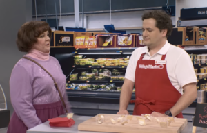 Esboço de amostra grátis do SNL mostra Melissa McCarthy cruzando os limites de Jeremy Culhanes mulher de suéter roxo fica ao lado de homem de camisa branca e avental vermelho