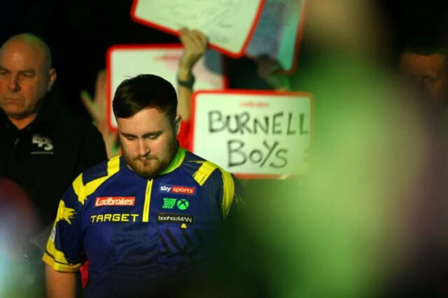Escolhas do Dia 1 do Campeonato Mundial de Dardos do O jogador de dardos Luke Littler observa enquanto é apresentado à multidão.