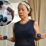 Uma mulher idosa levantando halteres azuis na sala de estar.