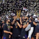 OG Anunoby (centro, L) e Karl-Anthony Towns erguem o troféu depois que o time derrotou o San Antonio Spurs por 124-113 para vencer o jogo do campeonato da Emirates NBA Cup.