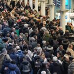 Os viajantes sentam-se com suas malas ao lado de um trem Eurostar na estação St. Pancras, em Londres, em 30 de dezembro de 2025, enquanto o serviço de trem Eurostar entre a Grã-Bretanha e a Europa continental é interrompido.