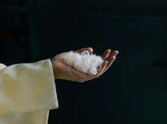 Everbloom construiu uma IA para transformar penas de galinha em caxemira A hand holds white fibers.