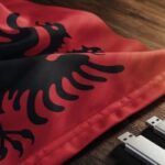 Uma bandeira albanesa e duas unidades USB sobre uma mesa. Ex-chefe de inteligência e filho condenados por acusações de jogos ilegais e segredos de estado na Albânia