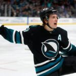 George Kittle (85), do San Francisco 49ers, tira uma foto do mascote do San Jose Sharks, SJ Sharkie, junto com seus companheiros de equipe do 49ers durante o jogo dos Sharks contra o Calgary Flames no segundo período no SAP Center em San Jose, Califórnia, na terça-feira, 16 de dezembro de 2025. (Nhat V. Meyer/Bay Area News Group)