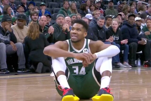 Giannis Antetokounmpo sai com distensão na panturrilha e preocupa o O jogador de basquete Giannis Antetokounmpo sentado na quadra durante um jogo.