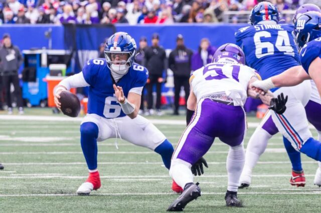 O quarterback Jaxson Dart nº 6 do New York Giants é forçado a sair do bolso pelo linebacker Blake Cashman nº 51 do Minnesota Vikings durante o primeiro tempo no MetLife Stadium, domingo, 21 de dezembro de 2025, em East Rutherford, Nova Jersey. 