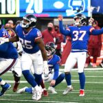 O chutador do New York Giants, Younghoe Koo #37, levanta os braços após chutar um field goal.