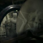 Um homem olha pela janela circular de uma porta, em preto e branco.