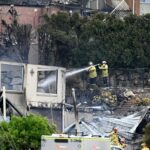 Firefighters ensure there are no flames left after a wildfire destroyed houses in Koolewong, Australia, Saturday, Dec. 6, 2025. (Dan Himbrechts/AAP Image via AP)