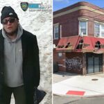 Um homem de gorro preto, óculos escuros, moletom cinza, casaco preto e calça escura carregando uma bolsa escura, andando em uma calçada parcialmente coberta de neve.