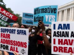 Isca racial: para contornar a lei, as faculdades incentivam os candidatos a escrever ‘redações de identidade’ Os manifestantes seguram cartazes dizendo