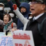 Uma mulher segura uma faixa que diz: