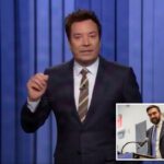 Jimmy Fallon de terno e gravata listrada, gesticulando com a mão direita diante de um fundo azul.