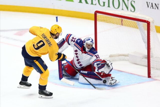 Jonathan Quick nº 32 do New York Rangers defende um chute de Filip Forsberg nº 9 do Nashville Predators no terceiro período na Bridgestone Arena em 21 de dezembro de 2025 em Nashville, Tennessee. 