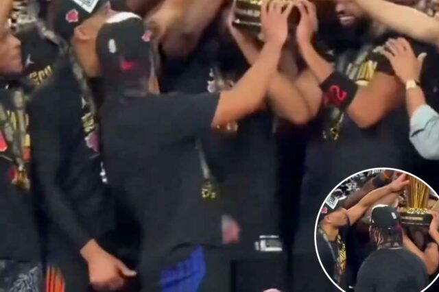 Josh Hart comemorando com sua equipe enquanto segura o troféu do campeonato.