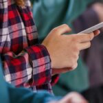 Grupo aproximado de adolescentes usando telefones celulares no corredor da escola