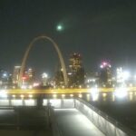 Um meteoro brilhando verde sobre Gateway Arch, no Missouri, à noite.