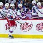 O pivô do New York Rangers, Mika Zibanejad (93), comemora um gol com seus companheiros no banco.