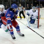 O pivô do New York Rangers, Mika Zibanejad (93), joga o disco contra o defensor do Vancouver Canucks, Tyler Myers (57), durante o segundo período.