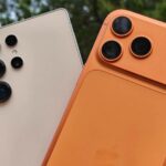 Mascote do Android segurando um iPhone com ícones que representam recursos como tela dividida, modo desktop e histórico de notificações.