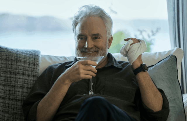 A man drinks from a glass and smiles