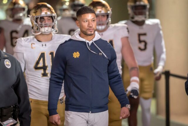 Notre Dame pressionando para manter Marcus Freeman em meio ao O técnico Marcus Freeman do Notre Dame Fighting Irish lidera seu time ao estádio para iniciar o segundo tempo de um jogo de futebol americano universitário contra o Stanford Cardinal em 29 de novembro de 2025 no Stanford Stadium em Palo Alto, Califórnia.