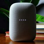 Ilustração de um alto-falante inteligente Google Home com o logotipo Gemini e Google Home na frente