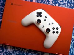 O controlador Stadia do Google acaba de receber uma grande atualização, cortesia do Steam Um controlador branco do Google Stadia no teclado de um Chromebook vermelho com um serviço de jogos aberto na tela. O laptop está sobre um fundo azul com gráficos prateados de imagens de videogame.
