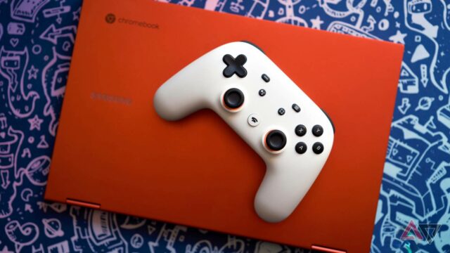 O controlador Stadia do Google acaba de receber uma grande Um controlador branco do Google Stadia no teclado de um Chromebook vermelho com um serviço de jogos aberto na tela. O laptop está sobre um fundo azul com gráficos prateados de imagens de videogame.