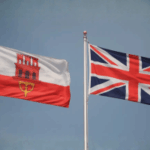 A bandeira de Gibraltar tremula ao lado da Union Jack. O deputado de Gibraltar sugere que o aumento dos impostos sobre jogos de azar no Reino Unido pode impactar o setor de jogos online.