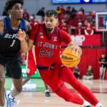 Bryce Hopkins nº 23 do St. John's Red Storm vai até a cesta enquanto Kaleb Banks nº 1 do DePaul Blue Demons dá a perseguição.