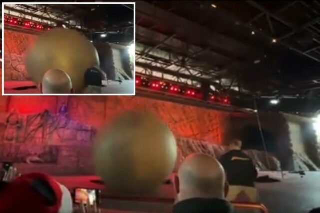 Uma grande bola cinza pairando no ar acima de um palco com uma pessoa visível.