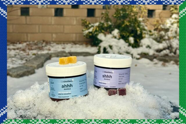 Agricultor segurando sementes de cânhamo nas mãos, com o sol poente e plantas de cânhamo ao fundo.