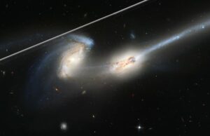 O lançamento de centenas de milhares de satélites ameaçará a pesquisa espacial, alertam cientistas Uma imagem de duas galáxias em interação com um raio de luz no canto superior esquerdo.