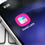 Ilustração 3D de quatro ícones do aplicativo Samsung Good Lock – Home Up, Nice Shot, NotiStar e Sound Assistant – dispostos horizontalmente em um fundo rosa com formas abstratas flutuantes.