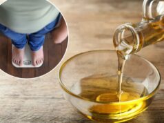 O óleo de cozinha mais popular na América pode contribuir diretamente para a obesidade: estudo Derramando óleo de cozinha de uma jarra de vidro em uma tigela de vidro sobre uma mesa de madeira.