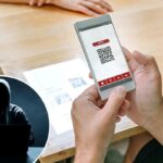 Um homem escaneando o código QR do cardápio de um restaurante em uma mesa com seu smartphone.