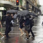 Sydney, Austrália - 2 de março de 2013: Pessoas atravessando a Pitt Street em Sydney durante uma forte chuva. Pedestres atravessando a rua em semáforos durante uma chuva.
