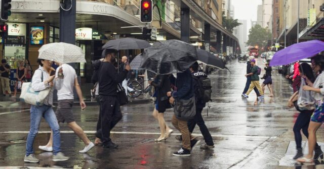O único estado pronto para ficar encharcado no dia de Sydney, Austrália - 2 de março de 2013: Pessoas atravessando a Pitt Street em Sydney durante uma forte chuva. Pedestres atravessando a rua em semáforos durante uma chuva.