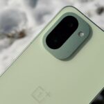 OnePlus 15R encostado em uma árvore nevada