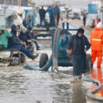 Jovens palestinos deslocados dentro de uma tenda inundada pela água da chuva no campo de refugiados de Bureij