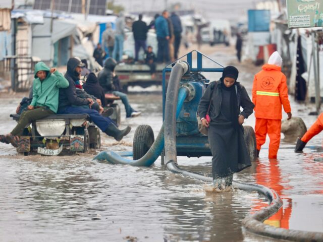 Jovens palestinos deslocados dentro de uma tenda inundada pela água da chuva no campo de refugiados de Bureij