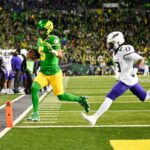 O quarterback do Oregon Ducks, Dante Moore (5), correndo para um touchdown enquanto o safety de James Madison Dukes, Tyler Brown (13), defende.