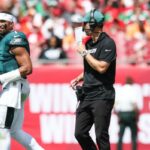 O técnico ofensivo do Philadelphia Eagles, Kevin Patullo, se comunica com o quarterback Jalen Hurts durante um intervalo.