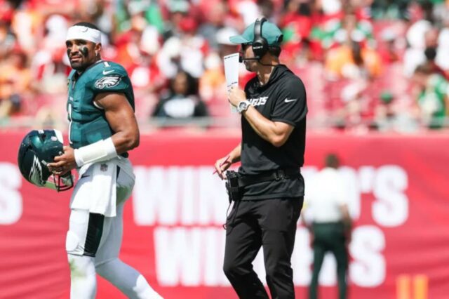 O técnico ofensivo do Philadelphia Eagles, Kevin Patullo, se comunica com o quarterback Jalen Hurts durante um intervalo.