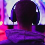 Jovem usando fone de ouvido e jogando videogame on-line - Casa isolada por surto de coronavírus