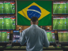 Painel do Senado aprova aumento de impostos sobre apostas esportivas no Brasil subindo para 18% até 2028 O mercado regulamentado de apostas do Brasil injetará US$ 5 bilhões na economia. O Brasil também aumentará o imposto sobre apostas de 12% para 18% até 2028. Um homem está em frente a várias telas de apostas esportivas que mostram jogos de futebol, com uma grande bandeira brasileira pendurada na parede atrás dele.